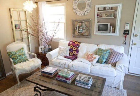 a small shabby chic living room done in neutrals, white vintage furniture, a wooden table, artworks and branches in a vase