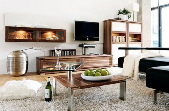 a stylish contemporary living room with simple wooden furniture, a black upholstered sofa, a glazed wall and some glass touches for a modern feel