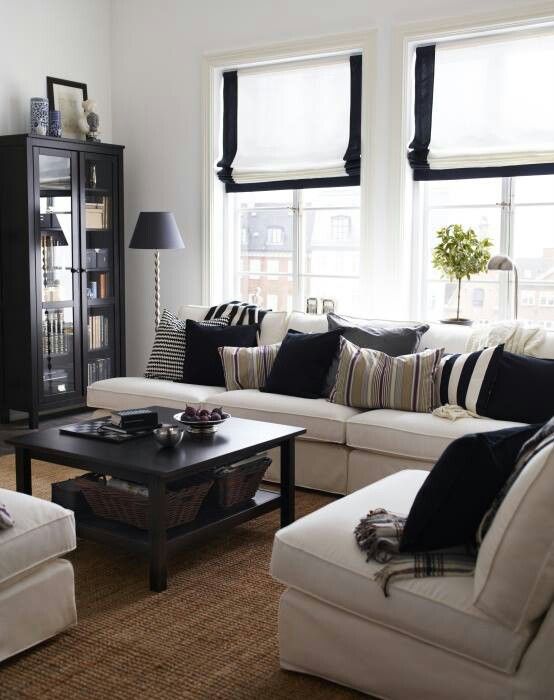 a contrasting farmhouse living room with touches of black for drama, with comfy furniture, a jute rug and a black coffee table and a vintage bookcase