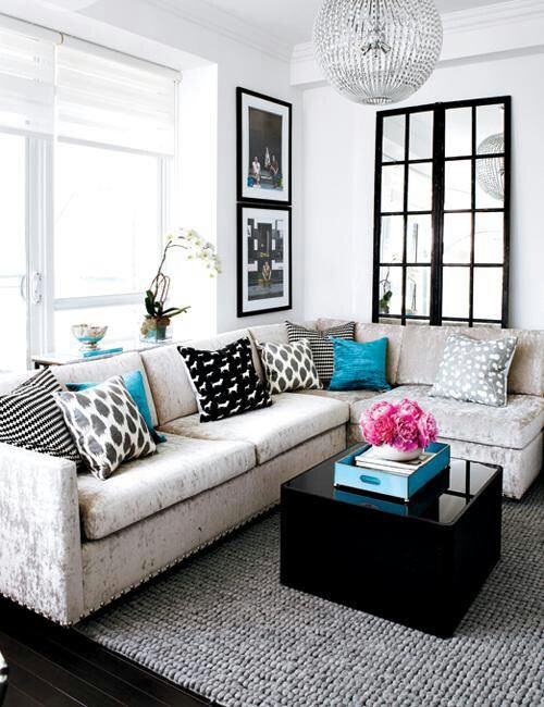 a small glam living room with modern furniture, a black shiny table, a crystal chandelier and bold artworks on the wall