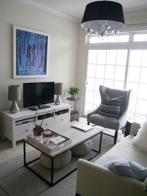a small contemporary living room done in a neutral color scheme, with comfy furniture and a black chandelier and an artwork