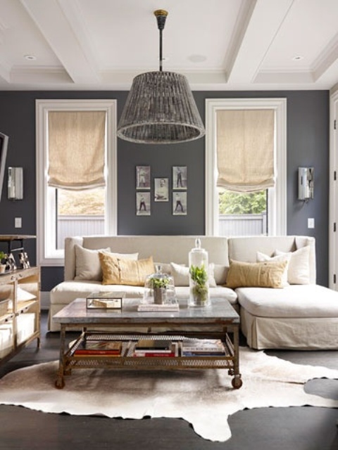 a small farmhouse living room with graphite grey walls, white furniture and metal and wood tables, a gallery wall and an animal skin rug