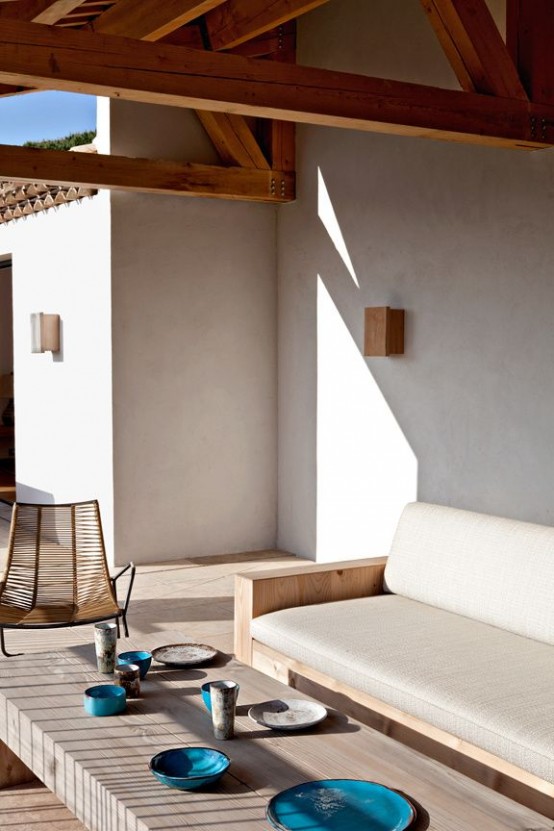 a neutral minimalist terrace with stylish sleek furniture, a low coffee table and turquoise and teal tableware for an accent