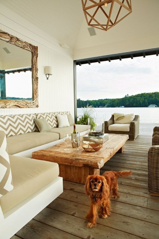 a coastal rustic terrace done in neutrals with a corner sofa with tan upholstery, a stained coffee table, wicker chairs and a lage mirror in a driftwood frame