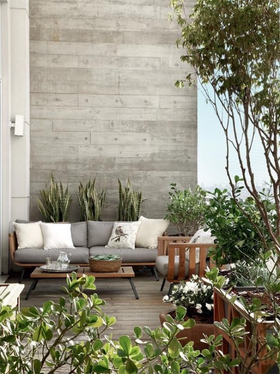 a neutral modern terrace with a stylish sofa and matching chairs, a low coffee table and lots of potted greenery and a tree around