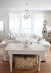 a white shabby chic living room with chic furniture, neutral textiles, a crystal chandelier and vintage accessories and decor