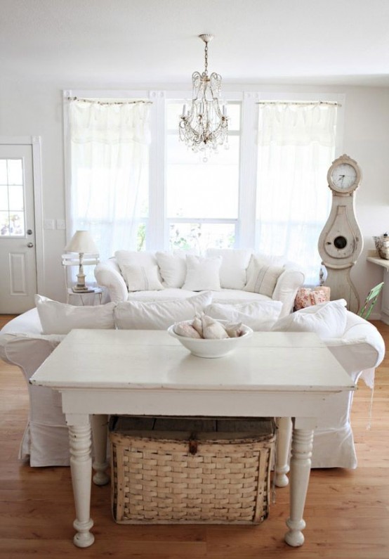 a white shabby chic living room with chic furniture, neutral textiles, a crystal chandelier and vintage accessories and decor