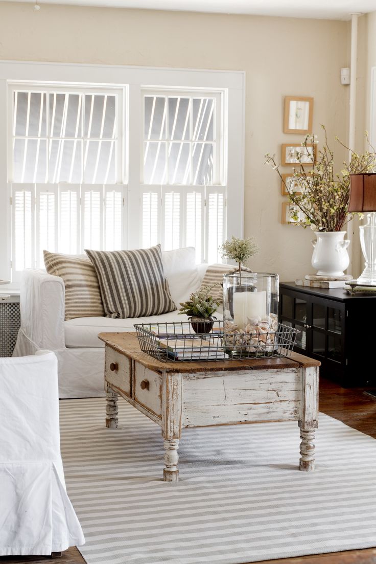 a farmhouse shabby chic living room with black and white furniture, striped pillows, greenery and a gallery wall