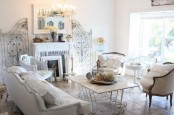 a neutral shabby chic living room with elegant furniture, a fireplace, a crystal chandelier, some screens and a table