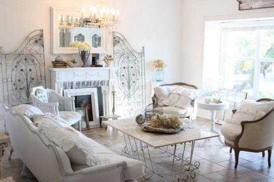 a neutral shabby chic living room with elegant furniture, a fireplace, a crystal chandelier, some screens and a table