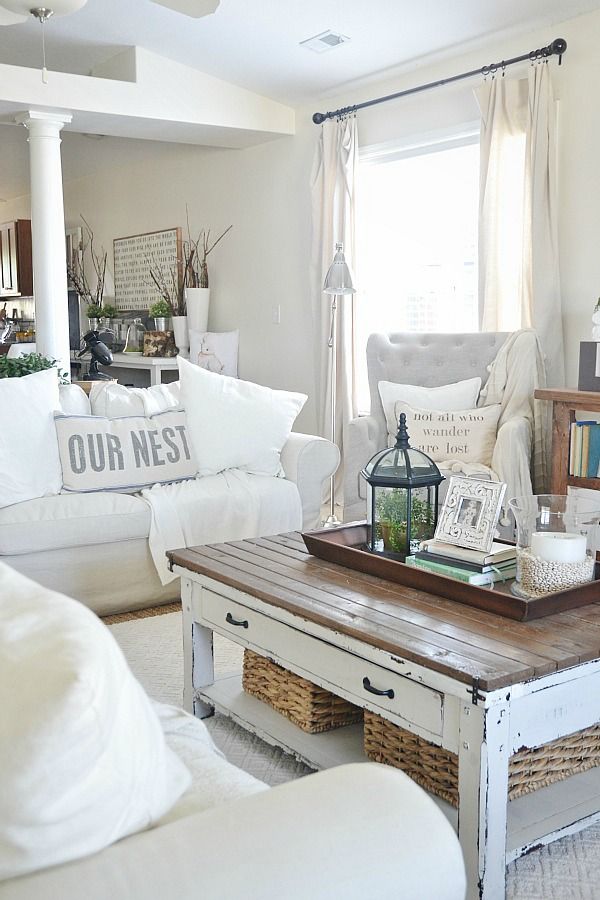 a neutral farmhouse shabby chic living room with white furniture, a low table, various baskets and table lamps is very stylish