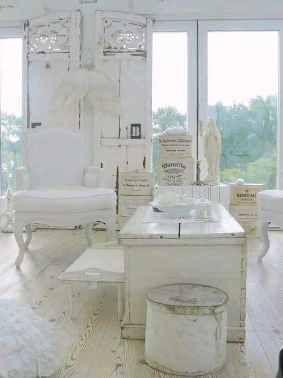 a white shabby chic living room with elegant furniture, a carved wooden screen, angel wings and antique accessories