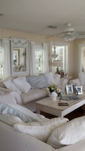 a neutral shabby chic living room with warm-colored walls, neutral furniture and pillows, a beaded chandelier and pastel touches here and there