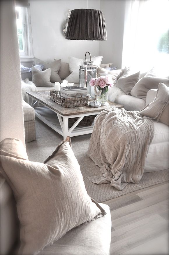a neutral and whitewashed shabby chic living room with simple and elegant furniture, a low table and pendant lamps