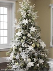 a Christmas tree with white and silver ornaments – balls, snowflakes, stars, snowy greenery and shiny ribbons