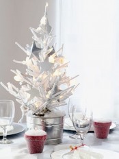 a mini snowy Christmas tree in a galvanized bucket, with lights and white star ornaments for a centerpiece