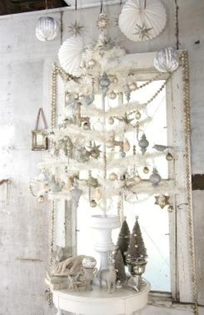 beautiful vintage Christmas decor in silver and white, with ornaments hanging down, garlands, paper pompoms and silver and white Christmas mini trees