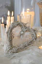 sophisticated white and silver Christmas decor of a white floral heart bow wreath and white candles is very refined