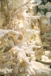a beautiful snowy Christmas tree with white, silver and gold ornaments and decorations is a very exquisite solution to try