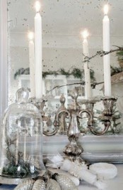 a vintage mirror, a silver candelabra with tall and thin candles, silver pinecones and a cloche with them for a refined and chic look