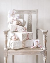 a whitewashed vintage chair with a stacked of beautifully wrapped gifts and silver and pearl ornaments is amazing part of your indoor Christmas decor