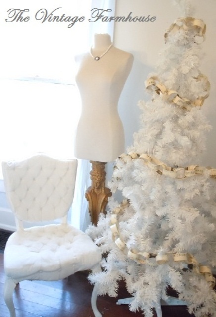 a white Christmas tree decorated with a paper chain garland and nothing else, a refined white chair for a vintage space