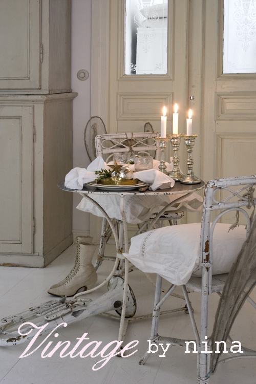 a white shabby chic Christmas tablescape for two, with elegant mercury glass candleholders and neutral and white porcelain
