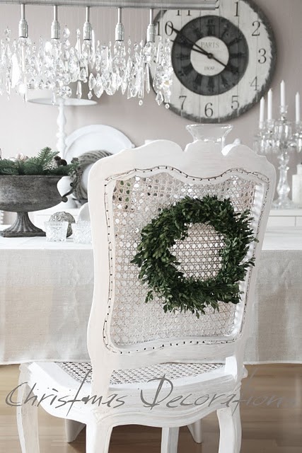 a white vintage space with a crystal chandelier and a candelabra, styled for Christmas with an evergreen wreath is a chic space