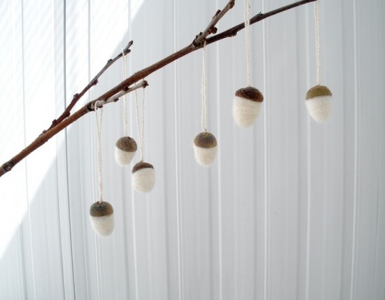 white felt acorns hanging on a branch is a cool and simple DIY fall decor idea