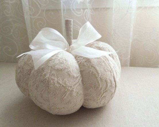 a refined neutral fabric pumpkin with a white ribbon bow is a pretty decoration that will last long