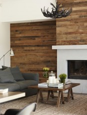 light stained weathered wood walls, a stained coffee table and an anlter chandelier make the space cozy and add a rustic feel