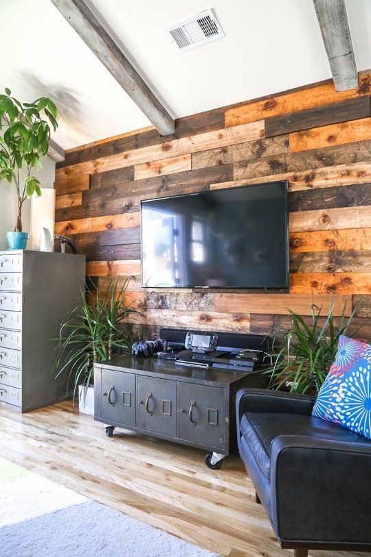 a weathered and stained wood accent wall softens the industrial-inspired living room with vintage touches