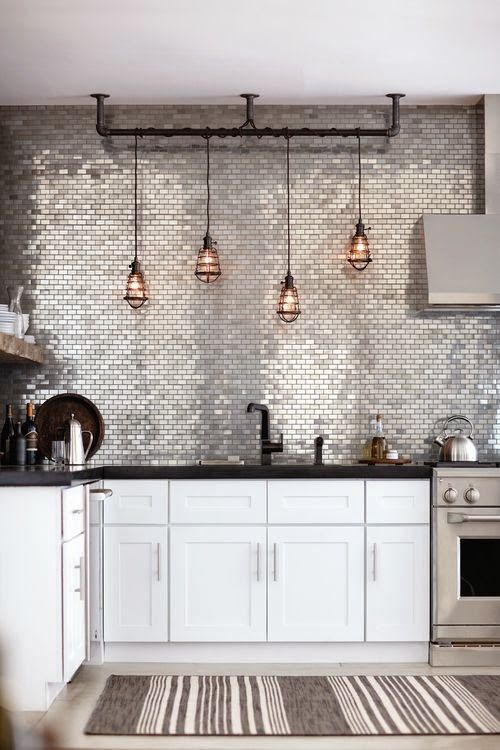a shiny silver tile accent wall and backsplash makes the monochromatic kitchen bolder and brighter