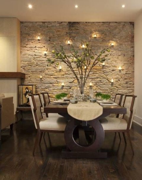 a textural stone wall accented with candles here and there adds interest to the refined and polished dining space
