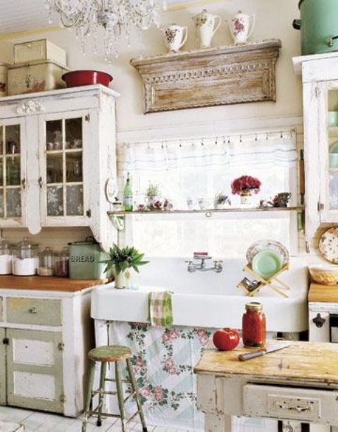 a vintage kitchen with shabby chic white and green cabinets, a shabby chic display shelf, a crystal chandelier and some plaid and floral textiles