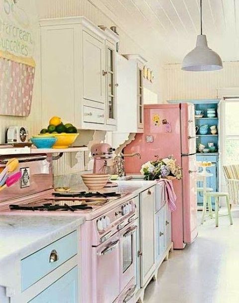 a candy-colored vintage kitchen with blue and pink cabinets, a pink fridge, a pink cooker, printed textiles and surfaces