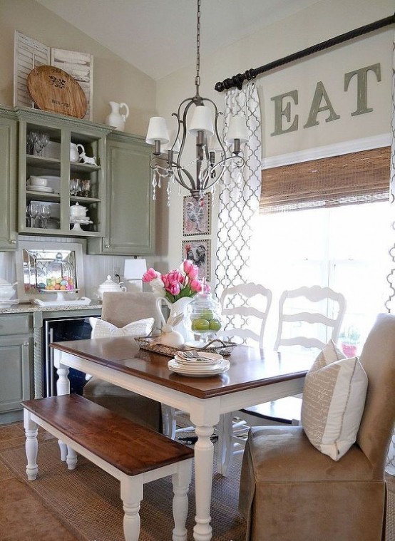 a chic vintage kitchen with green cabinets, a vintage dining set, a leather chair, a vintage chandelier and other vintage decor