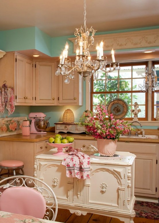 a fabulous vintage kitchen with neutral cabinets, a crystal chandelier, a refined white kitchen island, touches of pink and floral prints