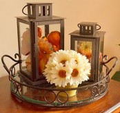 an exquisite tray with two large lanterns filled with blooms and pumpkins and a neutral floral arrangement