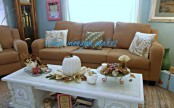 a white pumpkin on leaves, porcelain birds, fall leaves and twigs to decorate the coffee table