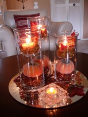 a mirror tray with fake fall leaves, candles, fall laves and glass candleholders for a fall coffee table