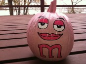 a pink pumpkin styled as M&Ms is a fun and playful idea for fall or Halloween decor