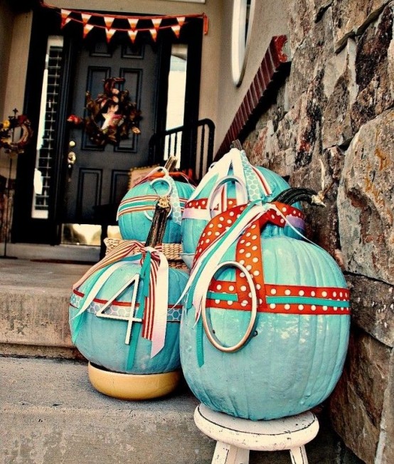 bright turquoise pumpkins with numbers and colorful printed ribbons compose a bright fall arrangement for outdoors