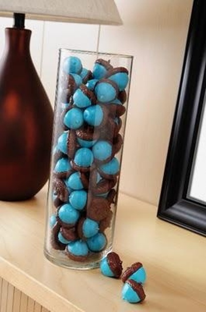 blue acorns in a tall glass vase are a nice and bright fall decoration to go for