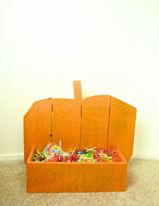 an orange pumpkin-shaped stand with candies is a cool decoration for outdoors and can be a fit for your entryway, too