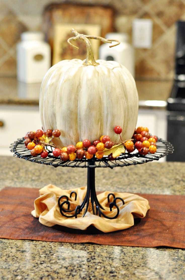 a metal stand with a faux white pumpkins and some faux berries is a classic fall decoration for a rustic feel