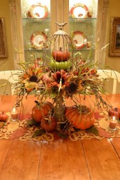 a vintage stand with faux pumpkins, faux blooms, grasses and twigs, plus candles around for a rustic centerpiece