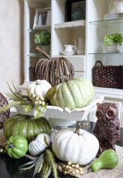 natural pumpkins and a vine one on a wooden stand and more veggies under it for a messy rustic touch