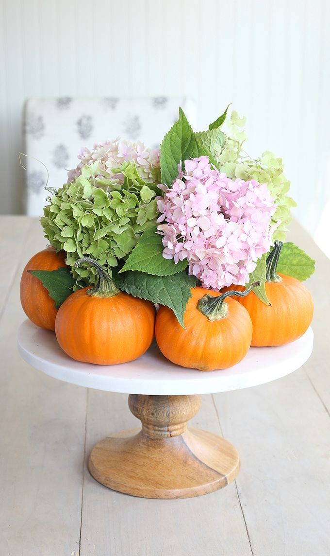 natural orange pumpkins with hydrangeas and leaves on a classic wooden stand is a cool centerpiece