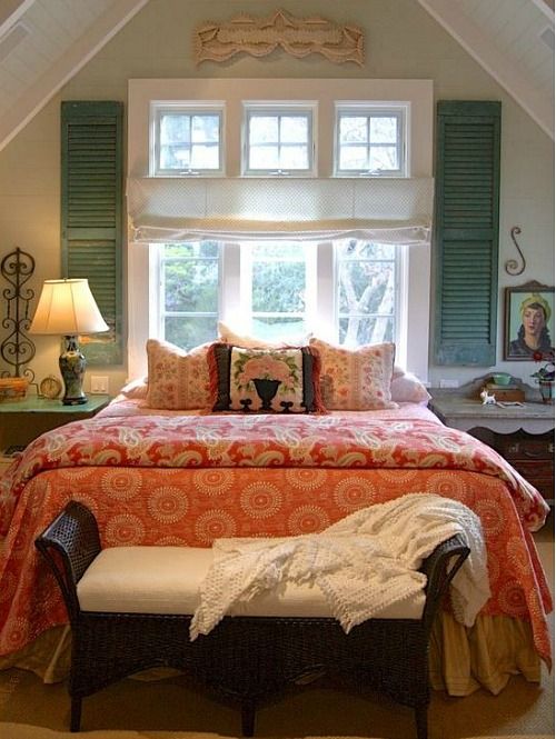 a vintage farmhouse bedroom done in turquoise and orange, lamps and curtains and printed bedding